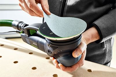 A man fits an abrasive to the sander