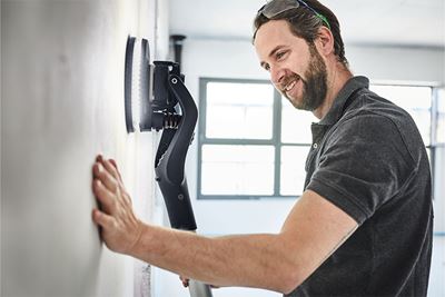 A tradesperson works on a wall with the Planex long-reach sander with lighting