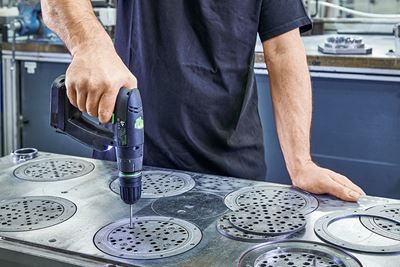 A tradesperson processes abrasive plates made from metal