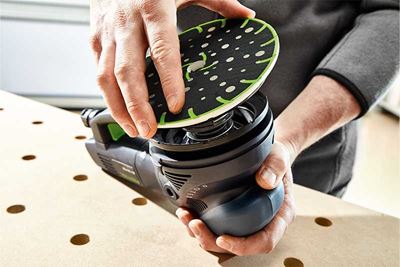 A tradesperson places a sanding pad on a Festool sander
